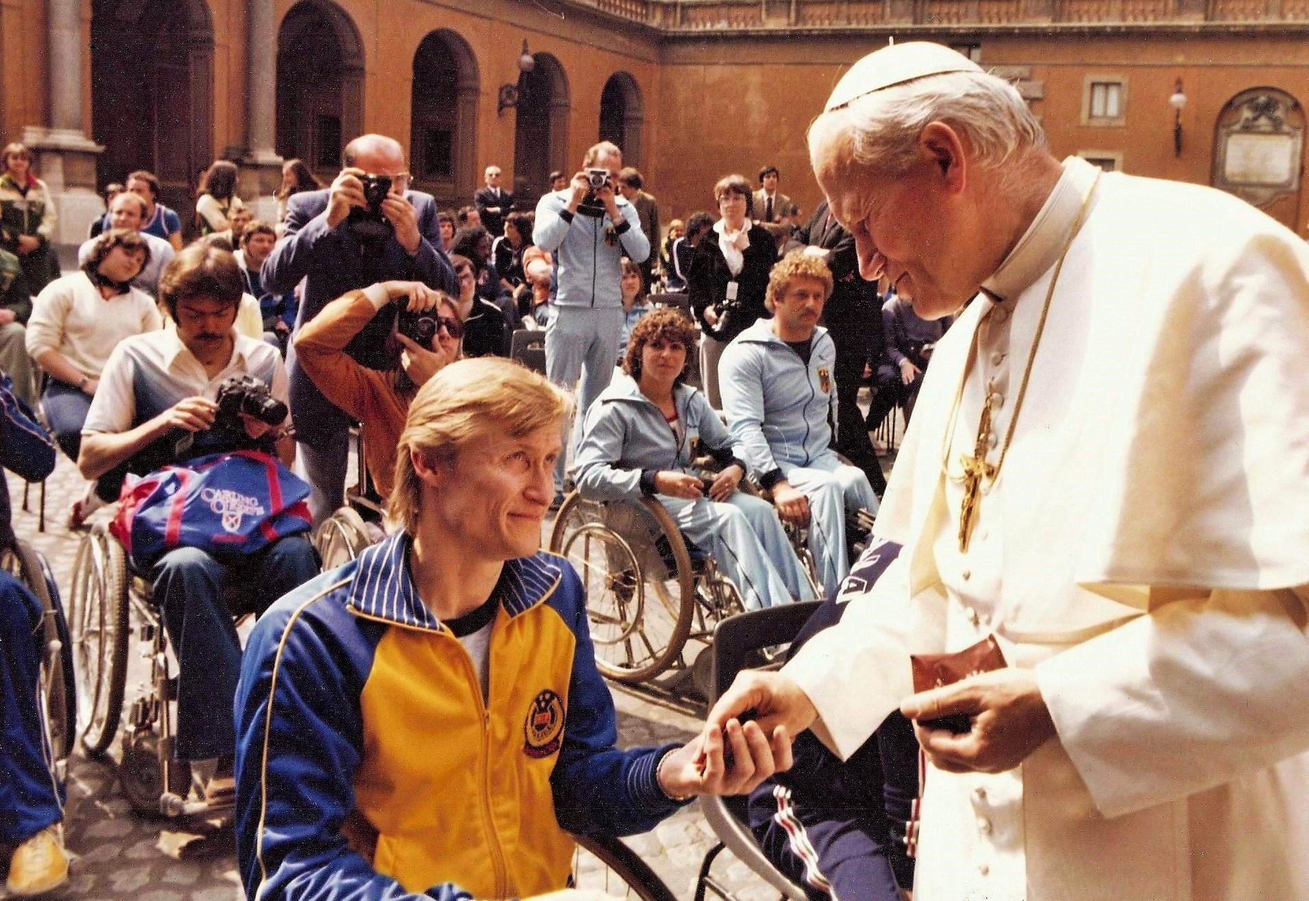 Man i rullstol mottar kors från påven
