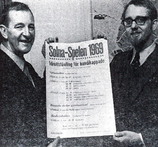 Två män håller affisch