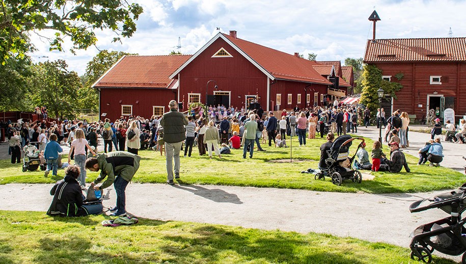 Folkmassa samlade framför röda byggnader under invigningen. 