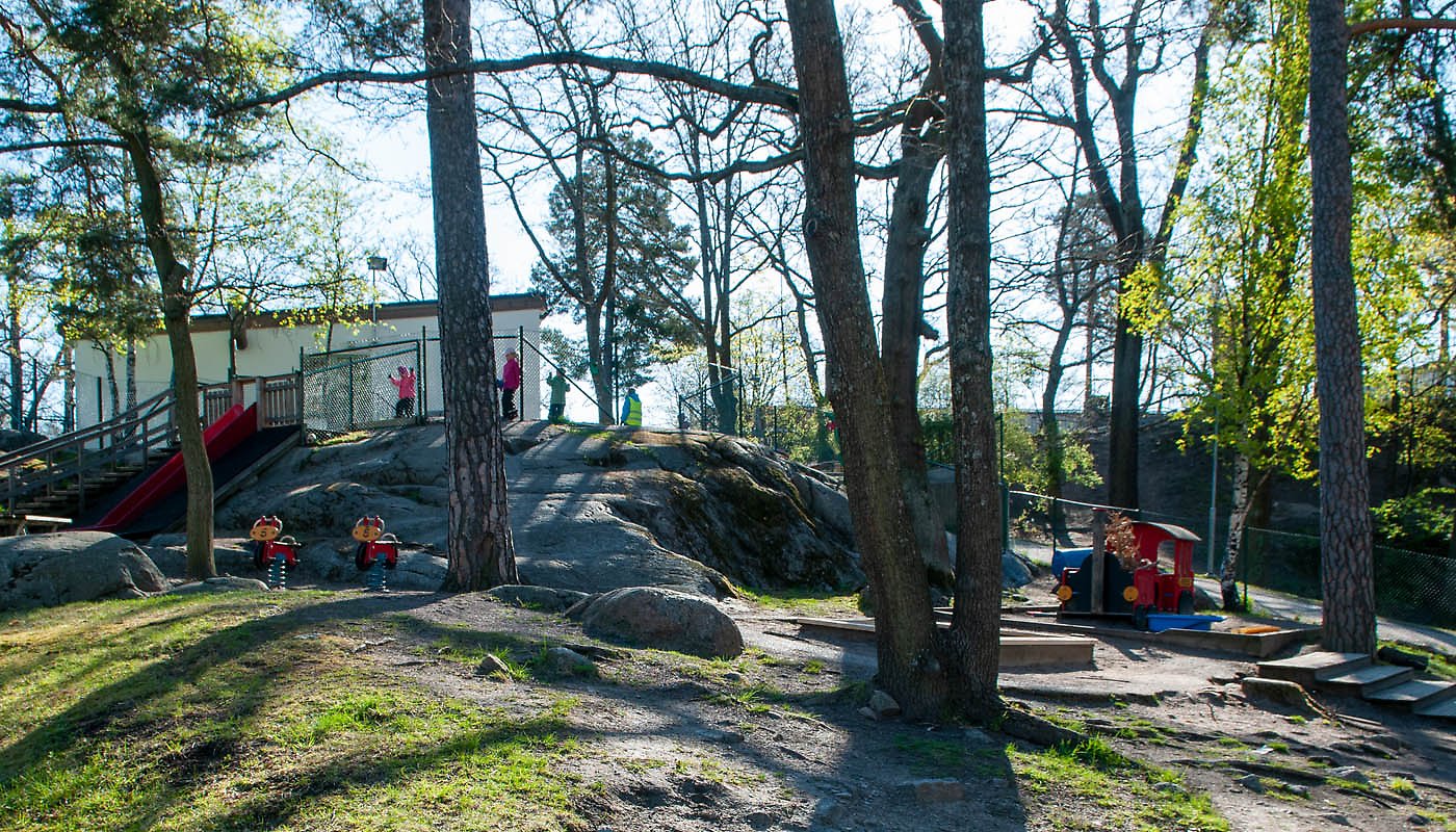 Gasellens förskola, utegården med lekställningar, träd och stenar.